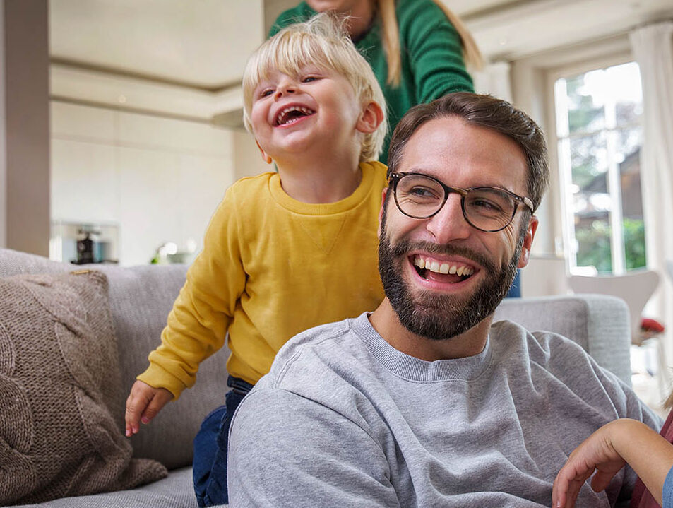Eine Familie spielt gemeinsam im Wohnzimmer. Sie lachen fröhlich.