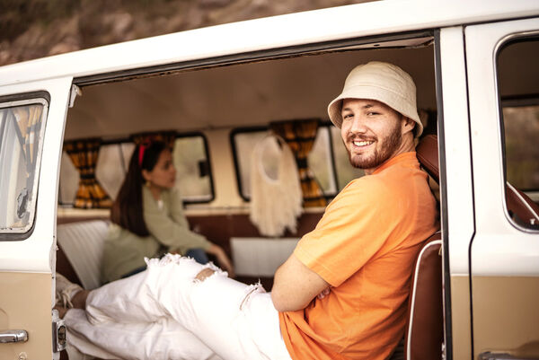 Ein Mann sitzt entspannt in einem Camper-Bus im Urlaub.