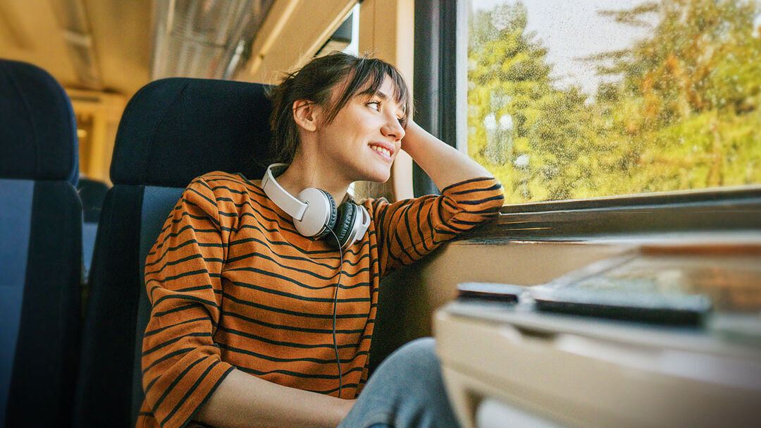 Junge Frau fährt im Zug und schaut aus dem Fenster