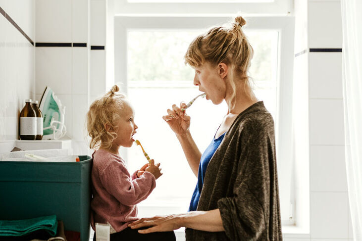 Eine Frau ist mit ihrer kleinen Tochter im Bad und sie putzen sich gemeinsam die Zähne.