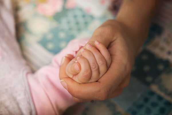 Die Hand eines Erwachsenen hält die Hand eines Babys.