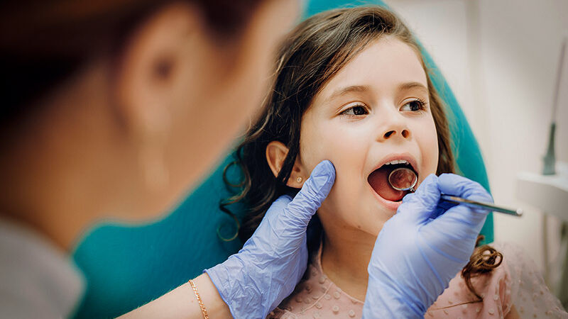 Ein junges Mädchen wird von einer Zahnärztin untersucht.