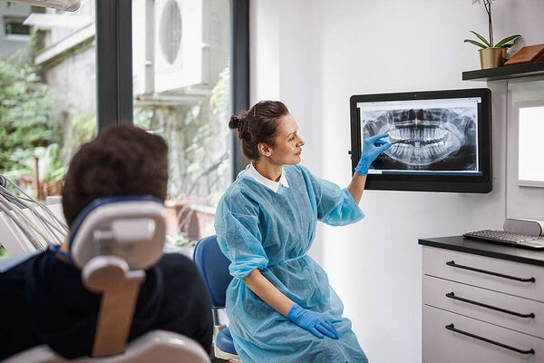 Eine Zahnärztin erklärt einem Patienten das Röntgenbild seines Kiefers.
