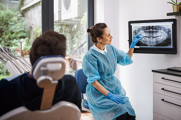 Eine Zahnärztin erklärt einem Patienten das Röntgenbild seines Kiefers.