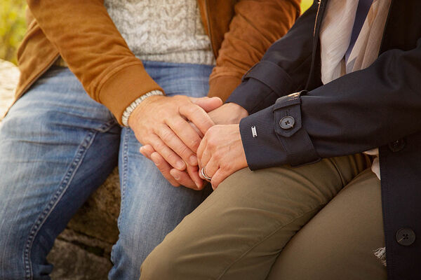 Ein Paar sitzt gemeinsam im Park und ein Mann hält die Hand seiner Partnerin.