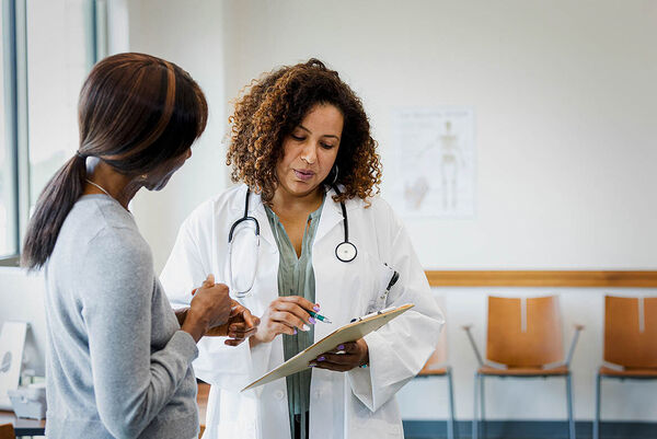 Eine Ärztin erklärt einer Frau die Untersuchungsergebnisse auf einem Dokument.