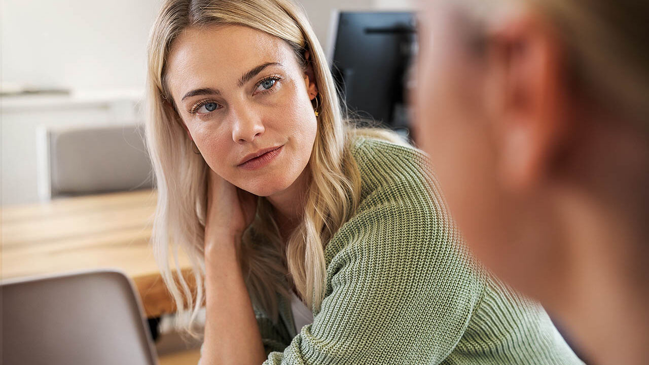 Eine Frau unterhält sich gerade mit einer anderen Frau, ihr Blick ist interessiert..