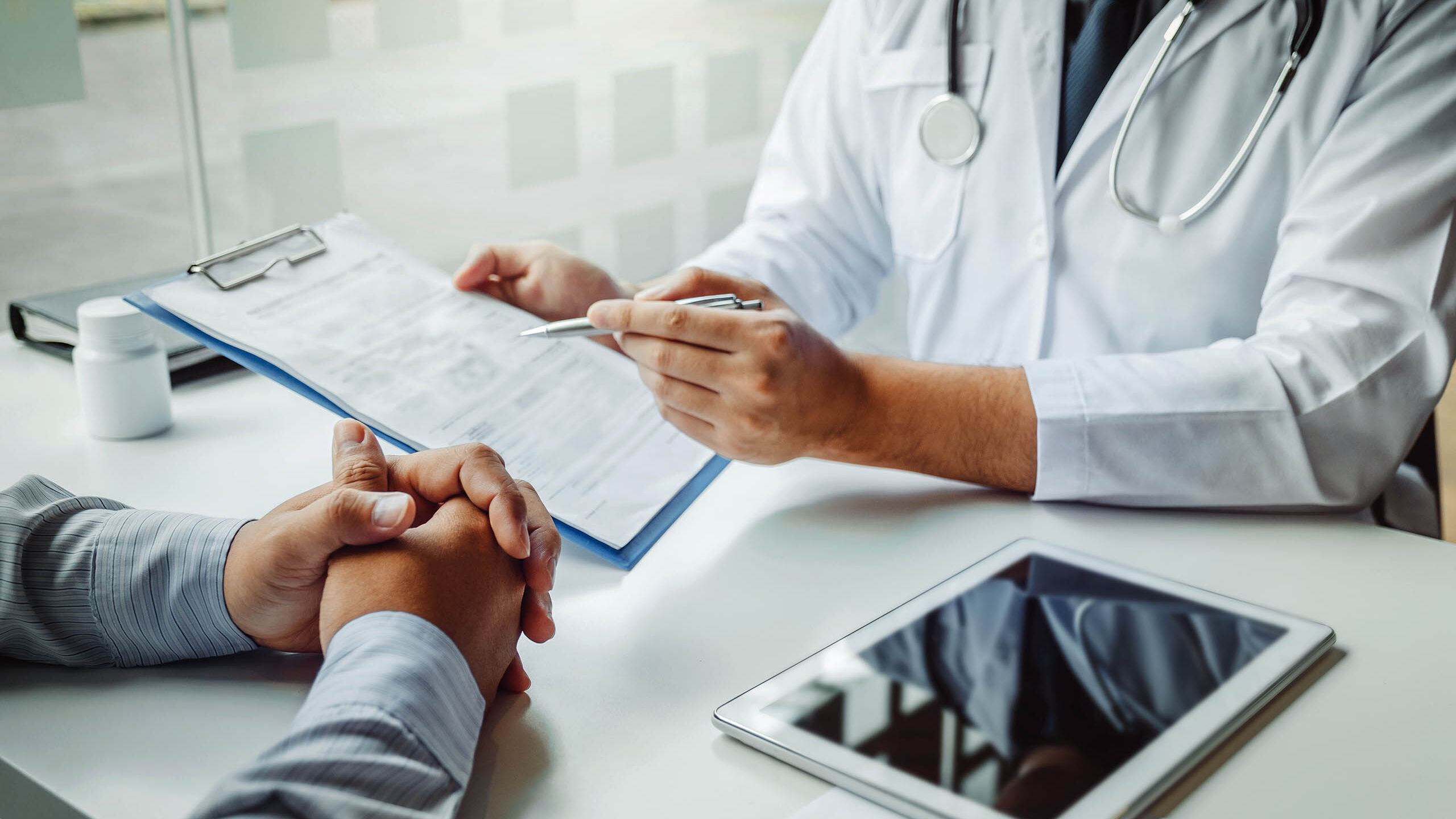 Ein Arzt und sein Patient gehen gemeinsam einen Fragebogen durch.