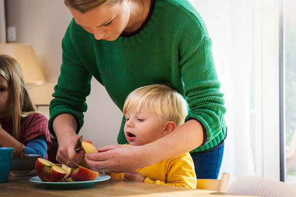 Eine Mutter schneidet einen frischen Apfel für ihren Sohn auf.