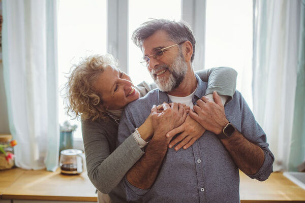 Ein älteres Paar umarmt sich glücklich in der Küche.
