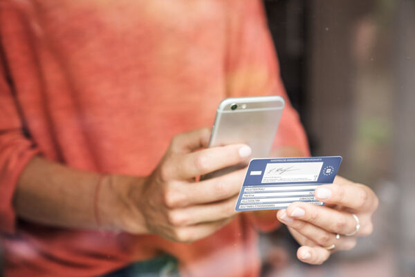 Eine Person macht ein Foto ihrer SBK-Gesundheitskarte mit ihrem Mobiltelefon.