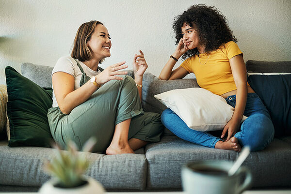 Zwei junge Frauen sitzen auf einem Sofa.