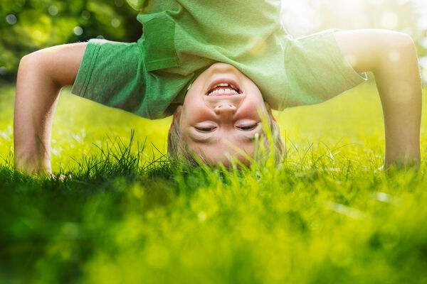 Kleiner Junge macht Kopfstand im Gras