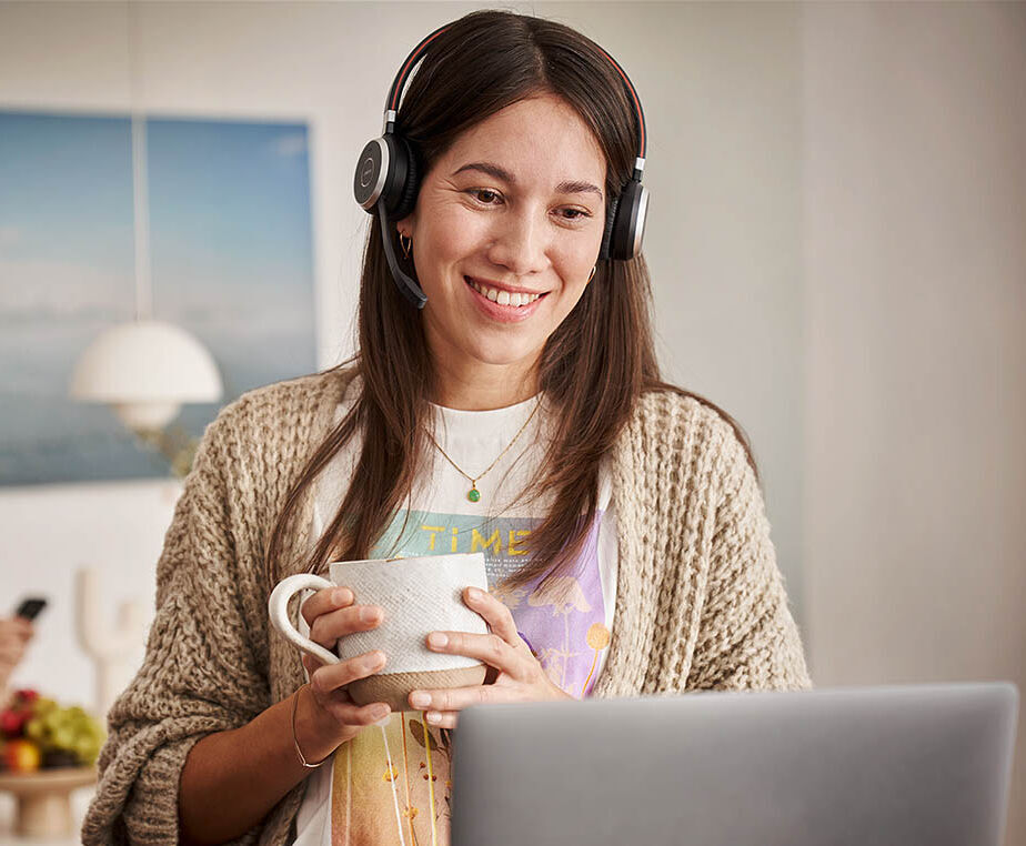 Eine Frau arbeitet im Homeoffice und nimmt gerade mit einem Headset an einer Videokonferenz teil.