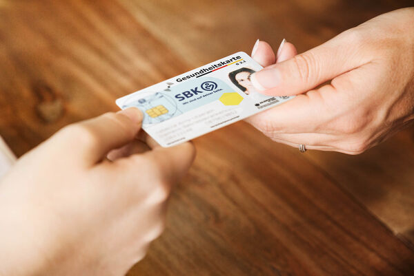 Two hands hold a SBK health care card