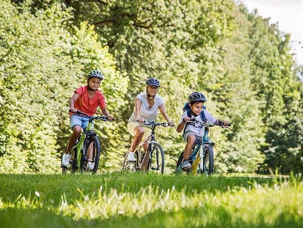 Eine Familie ist an einem sonnigen Sommertag mit dem Fahrrad in der Natur unterwegs.