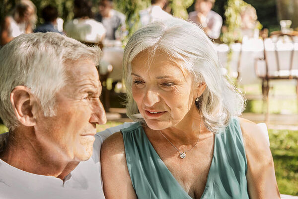 Ein älteres Paar sitzt zusammen auf einer Familienfeier und unterhält sich.
