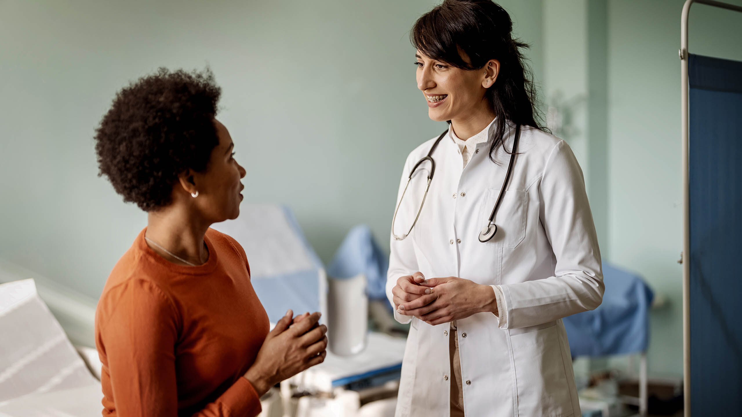 Eine Ärztin unterhält sich mit ihrer weiblichen Patientin im Behandlungsraum.