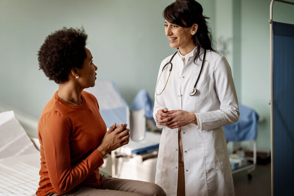 Eine Ärztin unterhält sich mit ihrer weiblichen Patientin im Behandlungsraum.