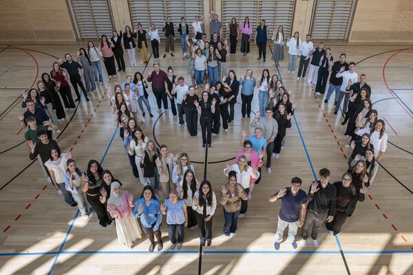 Auszubildende stehen in Herzform in einer Turnhalle