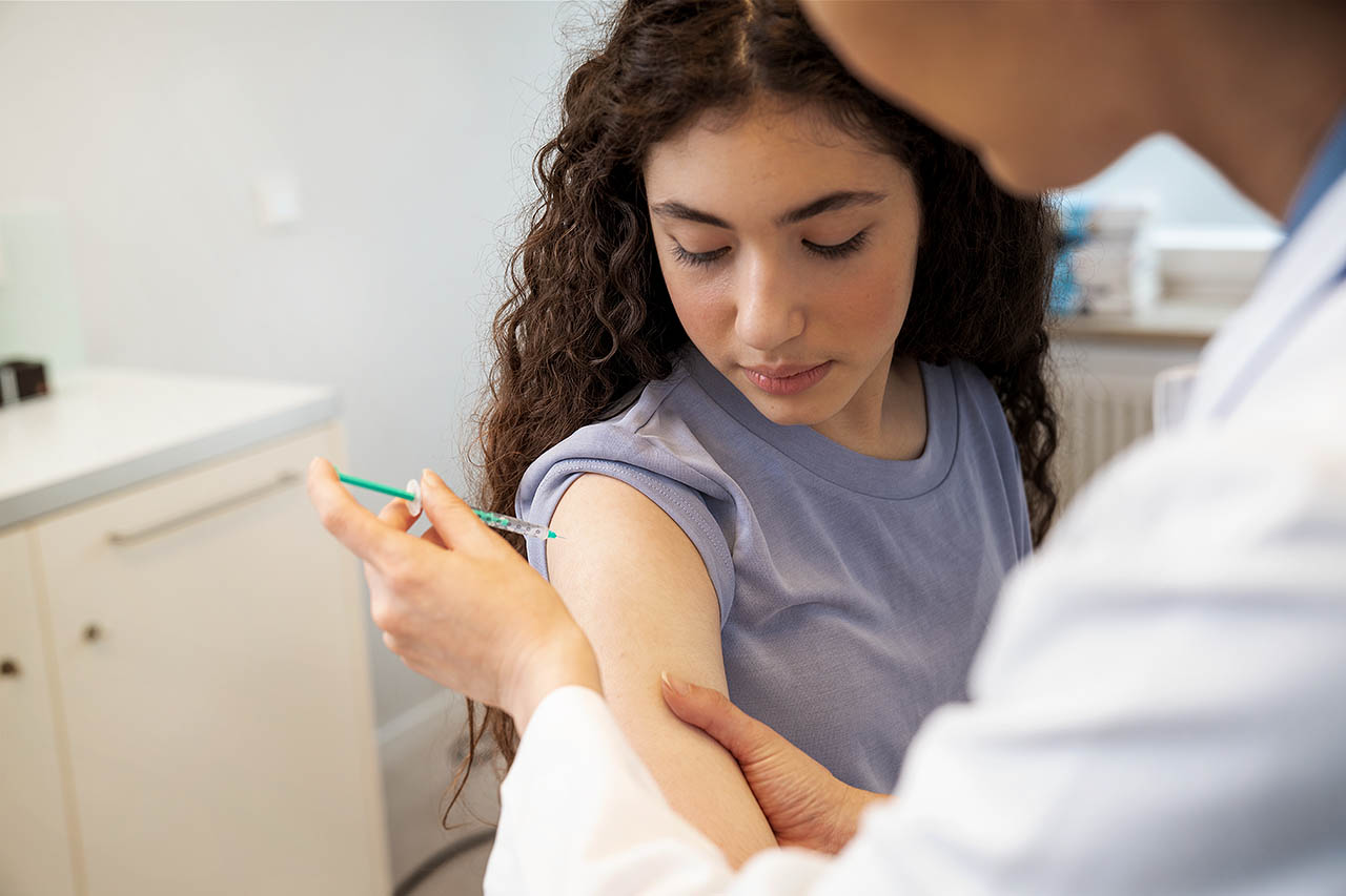 Ein Teenager bekommt von einer Ärztin eine Impfung in den Oberarm.