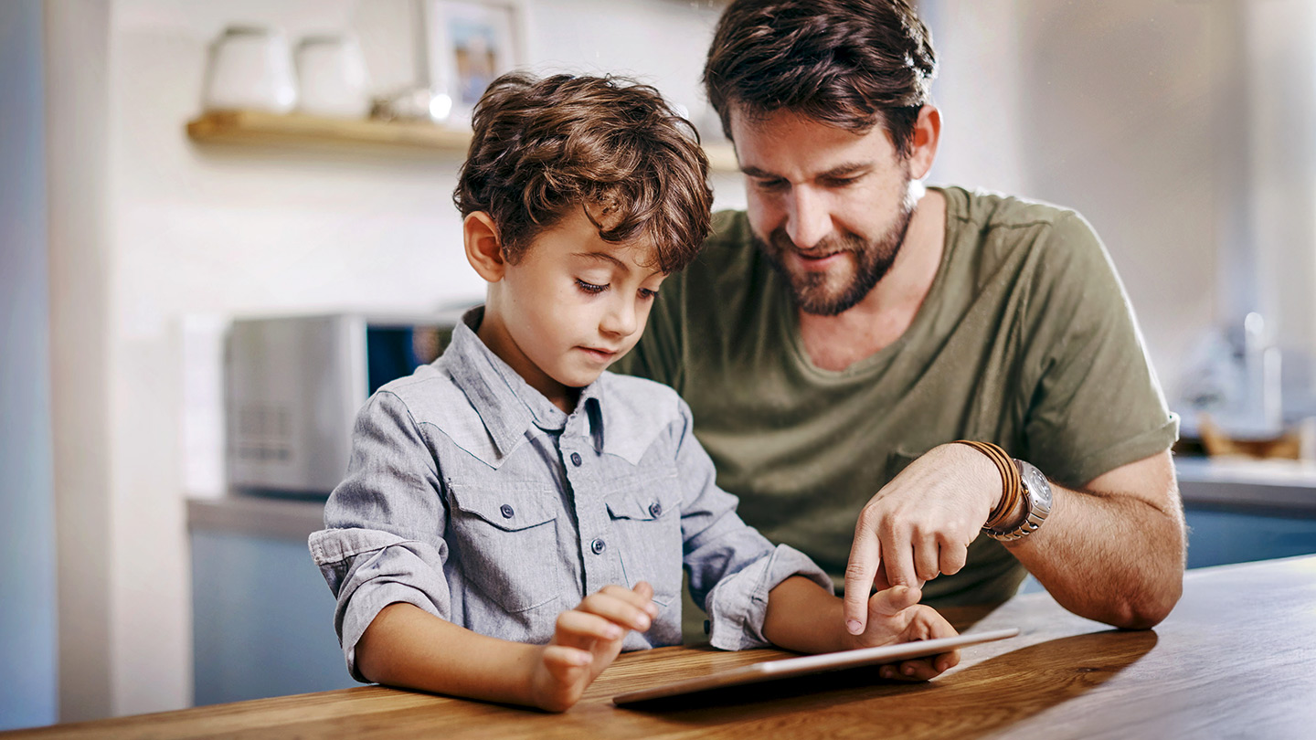 Vater, der mit seinem Sohn zusammensitzt und ein Tablet benutzt